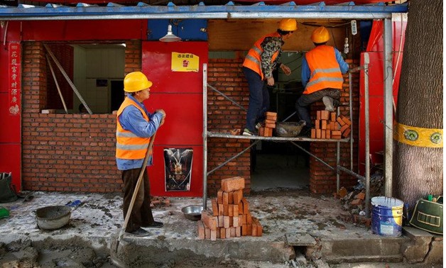 Workers build a brick wall across the front of a restaurant in a hutong alley in Beijing, China May 5, 2017 - REUTERS