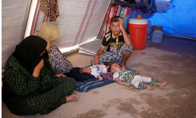 The two children of an Iraqi man whose family says he was an Islamic State militant lie on the ground at a tent in the Jada camp south of Mosul Iraq - REUTERS