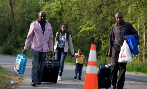 A family that said they are from Haiti walks to the US-Canada border from Roxham Road in Champlain - Reuters