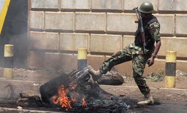 A Kenyan policeman kicks a burning tire set on fire by protesters supporting opposition leader Raila Odinga during clashes in Kisumu, Kenya August 11, 2017.
