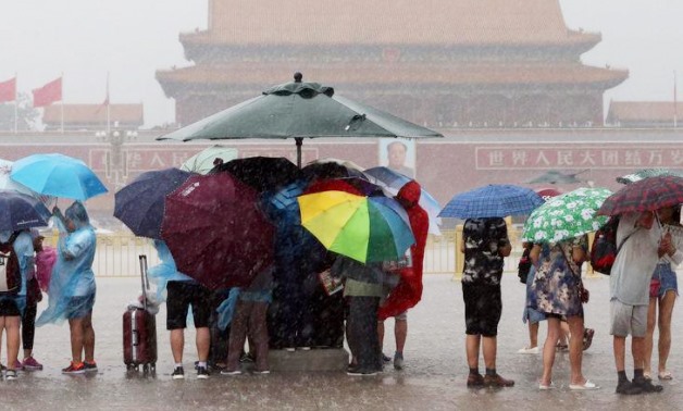 Tourists hold umbrellas as they visit Tiananmen Square during a rainstorm in Beijing, China August 12, 2017 – REUTERS/Stinger