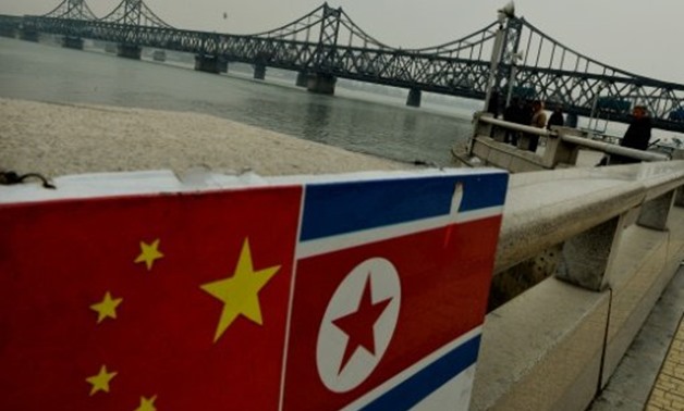 © AFP/File | The Chinese and North Korean flags attached to a railing as trucks carrying Chinese-made goods cross into North Korea on the Sino-Korean Friendship Bridge at the Chinese border town of Dandong on December 18, 2013
