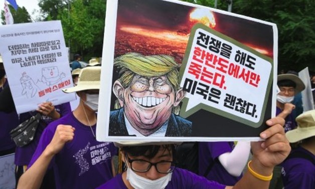 © AFP | South Korean protesters hold placards at an anti-Trump rally
