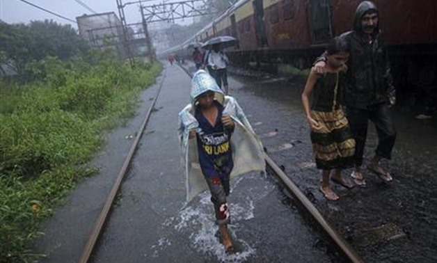 People walk over waterlogged railway tracks after getting off a stalled train during heavy monsoon rains - REUTERS