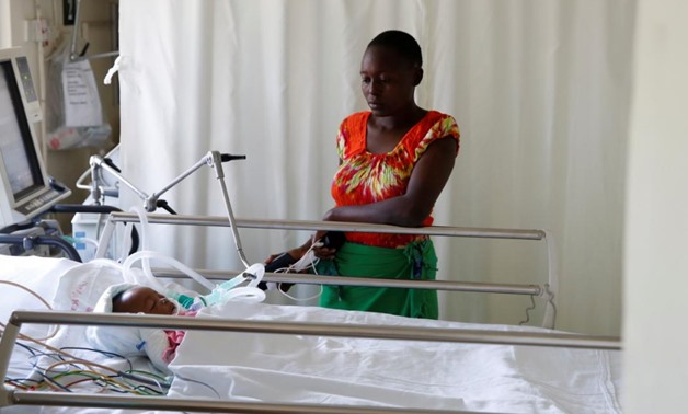 Lenzer, mother of six month-old Samantha Pendo, stands next to her bed as the girl remains in critical condition in the Intensive Care Unit of Aga Khan Hospital in Kisumu