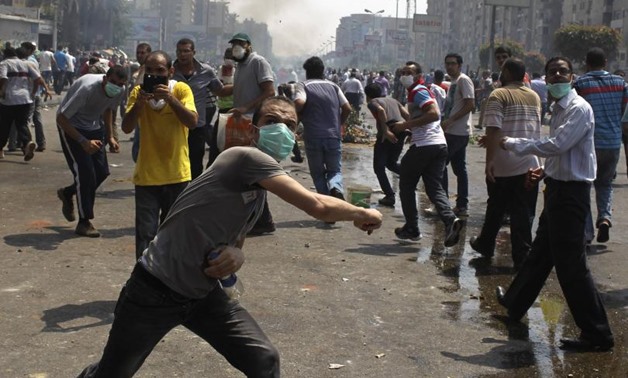 FILE- Members of the Muslim Brotherhood throw stones at riot police and army personnel during clashes in Cairo - Reuters