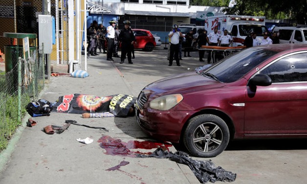 A body is seen lying next to a rifle after suspected gang members attacked Roosevelt Hospital in Guatemala City - REUTERS