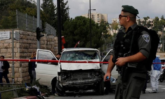 An Israeli border police officer walks in front of the vehicle of a Palestinian motorist who rammed into pedestrians, near the scene of an attack in Jerusalem November 5, 2014 - REUTERS
