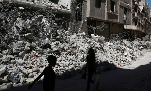  Children walk past rubble of damaged buildings at Ain Tarma, eastern Damascus suburb of Ghouta - REUTERS