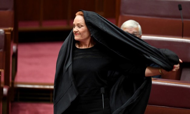 Australian One Nation party leader, Senator Pauline Hanson pulls off a burqa in the Senate chamber at Parliament House in Canberra - Reuters