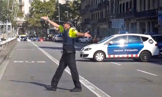 A still image from video shows a police officer gesturing while walking across a road, after a van crashed into people in the centre of Barcelona, Spain, August 17, 2017. REUTERS