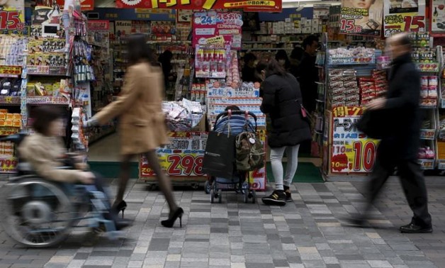 File Photo - A woman with a baby buggy looks at items outside a discount store at a shopping district in Tokyo, Japan, February 25, 2016.
Yuya Shino