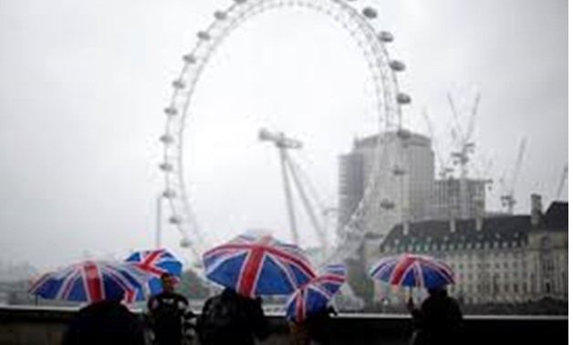 Tourists carrying Union Flag umbrellas shelter from the rain in front of the London Eye wheel in London, Britain, August 9, 2017- REUTERS