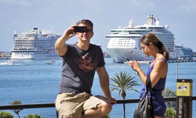 A tourist takes a selfie with cruise ships in the background in Palma de Mallorca - Reuters