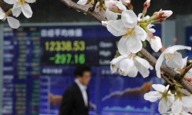 FILE PHOTO - A man walks past an electronic screen displaying the Nikkei share average as cherry blossoms are in full bloom outside a brokerage in Tokyo March 22, 2013.
Toru Hanai (JAPAN