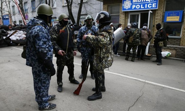 Armed men stand in front of police headquarters in Slaviansk, April 12, 2014 - reuters