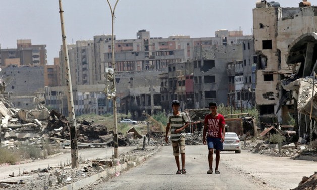 Men walk near destroyed buildings in Sabri, a central Benghazi district - reuters