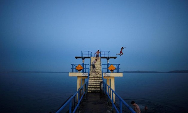 A man jumps off a diving board at night in Salthill, County Galway, Ireland-REUTERS/Clodagh Kilcoyne
