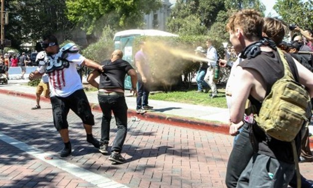 © AFP | Joey Gibson (black t-shirt), leader of the alt-right Patriot Prayer group, gets pepper sprayed by leftist counter demonstrators in Berkeley, California