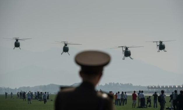 © AFP/File | A North Korean soldier watches as Hughes MD-500 helicopters perform a fly-by during the first Wonsan Air Show in September 2016
