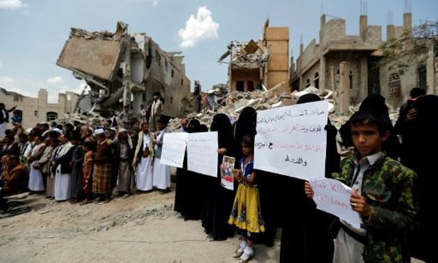 Yemenis stand in protest amidst the debris of a house, hit in an air strike on a residential district, in the capital Sanaa on August 26, 2017