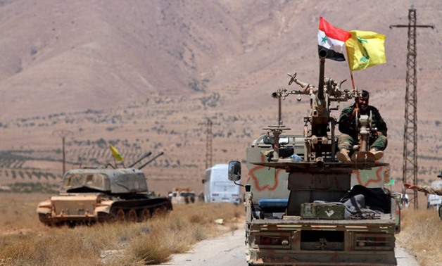 Hezbollah and Syrian flags flutter on a military vehicle in Western Qalamoun - REUTERS