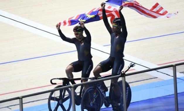 zizul Hasni Awang (left) and Firdaus Shah Sahrom (right) hold Malaysia's flag after winning gold and silver in the men's sprint cycling at the 29th Southeast Asian Games