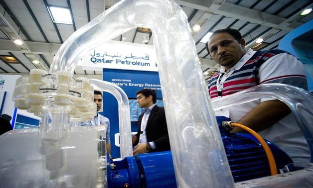 Visitors look at an oil purification unit at the Qatar Petroleum Company booth- Reuters