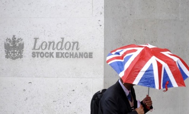 
A worker shelters from the rain under a Union Flag umbrella as he passes the London Stock Exchange in London,