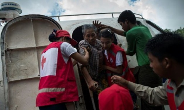 © AFP/File | Members of Myanmar's Red Cross help elder woman, who is fleeing a conflict area, upon arriving in Sittwe jetty, in Rakhine State on August 30, 2017
