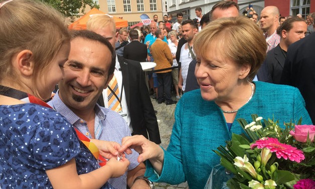 German Chancellor Angela Merkel meets Salim Jarrah on the square in Greifswald - REUTERS