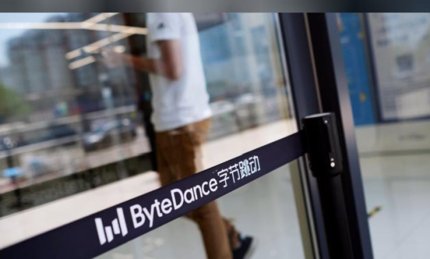 FILE PHOTO: A man walks by a logo of Bytedance, the China-based company which owns the short video app TikTok, or Douyin, at its office in Beijing, China July 7, 2020.