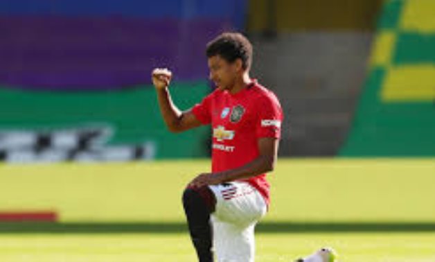 Manchester United's Jesse Lingard raises a fist as he kneels in support of the Black Lives Matter campaign before the match,  Catherine Ivill/Pool via REUTERS