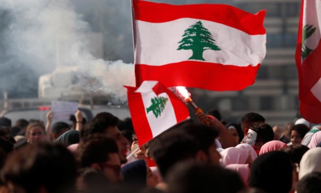 University students light a torch and wave Lebanese flags during anti-government protest in Beirut, Lebanon, November 6, 2019. REUTERS/Goran Tomasevic