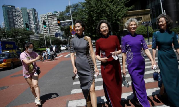 Members of an internet celebrity model group "Glamma Beijing" wearing traditional Chinese dresses walk across a street during a video shooting -  REUTERS/Tingshu Wang