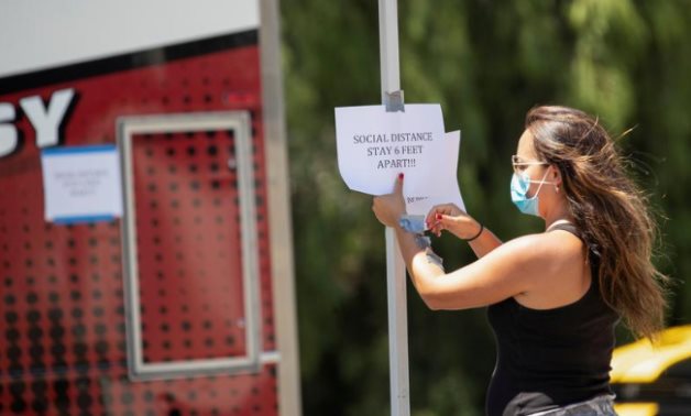 FILE PHOTO: A person places a sign reminding about social distancing on the set of the film "7th & Union" during the outbreak of (COVID-19), in Pomona, California, U.S., July 8, 2020. REUTERS/Mario Anzuoni
