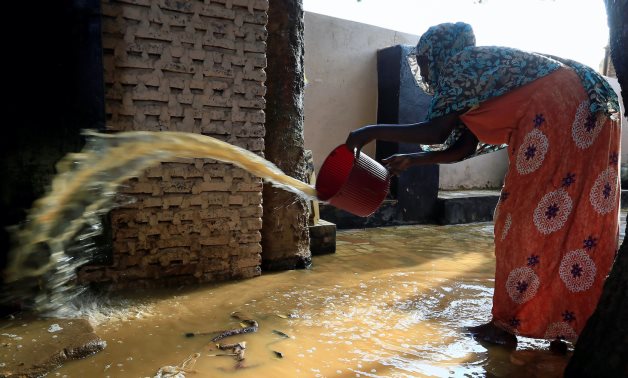 A resident pours out the waters of the Blue Nile floods from her backyard within the Al-Ikmayr area of Omdurman in Khartoum, Sudan August 27, 2020. REUTERS/Mohamed Nureldin Abdallah