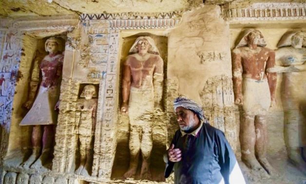  An Egyptian archaelogical laborer is seen walking near deities in a newly discovered tomb at Saqqara necropolis, on Saturday. (AFP)