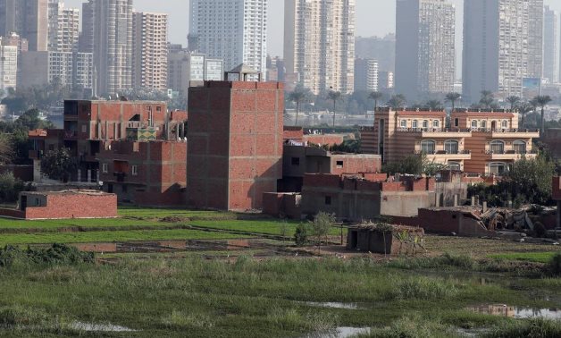 Buildings on farmland on a Nile River island with high rise buildings in the background - Reuters