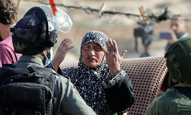 A Palestinian woman reacts in front of Israeli forces as Israeli machineries demolish a house near Hebron in the Israeli-occupied West Bank