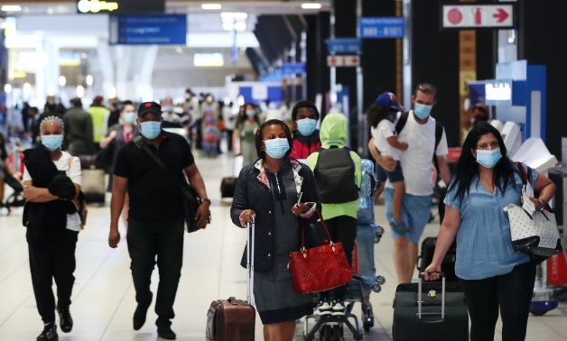 Passengers wearing protective masks walk to the check-in counters at the O.R. Tambo International Airport in Johannesburg, South Africa, December 22, 2020. REUTERS/Siphiwe Sibeko