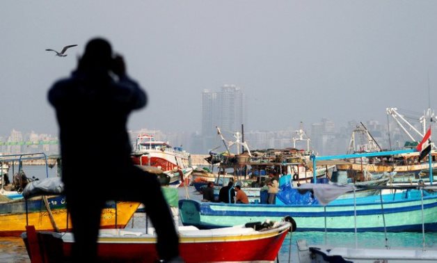 A man takes a picture of fishing boats docked along the Mediterranean Sea, north of Cairo, Egypt December 6, 2020 - Reuters