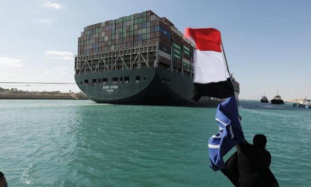 A citizens waves the Egyptian flag as the giant Ever Given ship could be tugged successfully toward The Bitter Lake – Suez Canal Authority