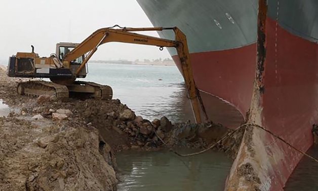 Tiny excavator removes mud and sands around the Ever Given when it went aground in the Suez Canal- press photo
