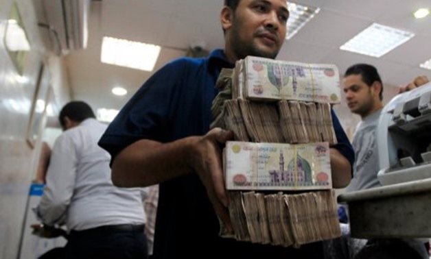 An employee carries money at an exchange office in downtown Cairo – Reuters/Amr Dalsh