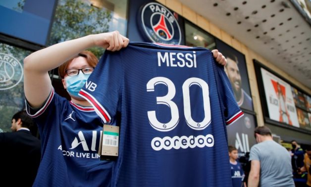 A fan poses with a Paris St Germain Lionel Messi football jersey, Reuters