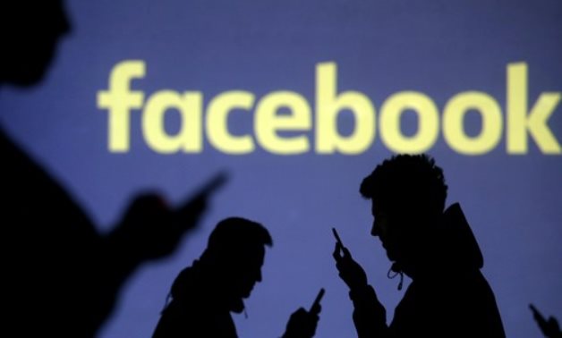 FILE PHOTO: Silhouettes of mobile users are seen next to a screen projection of Facebook logo in this picture illustration taken March 28, 2018. REUTERS/Dado Ruvic/Illustration