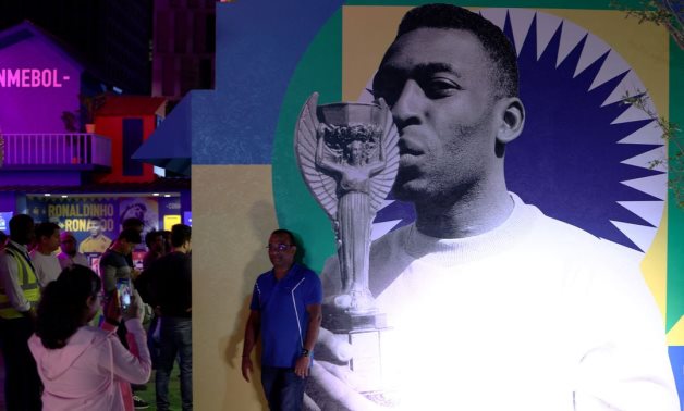 A fan poses in front of a picture of Brazil's Pele at CONMEBOL - Tree of Dreams exhibition REUTERS/Marko Djurica