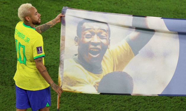 Brazil's Neymar carries a banner of former Brazil player Pele after the match REUTERS/Pedro Nunes
