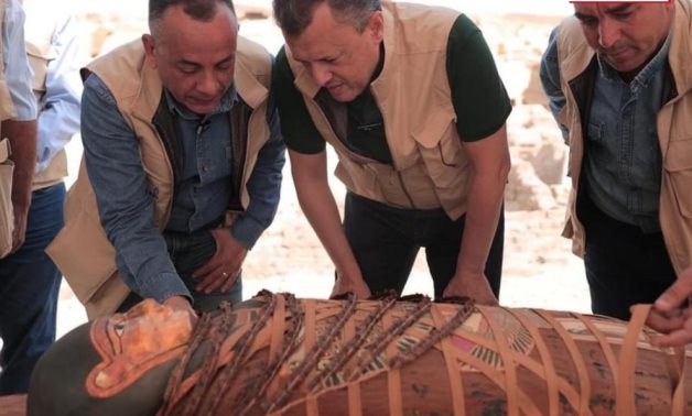 File: Ahmed Eissa and Mostafa Waziri examining one of the newly discovered colorful coffins.